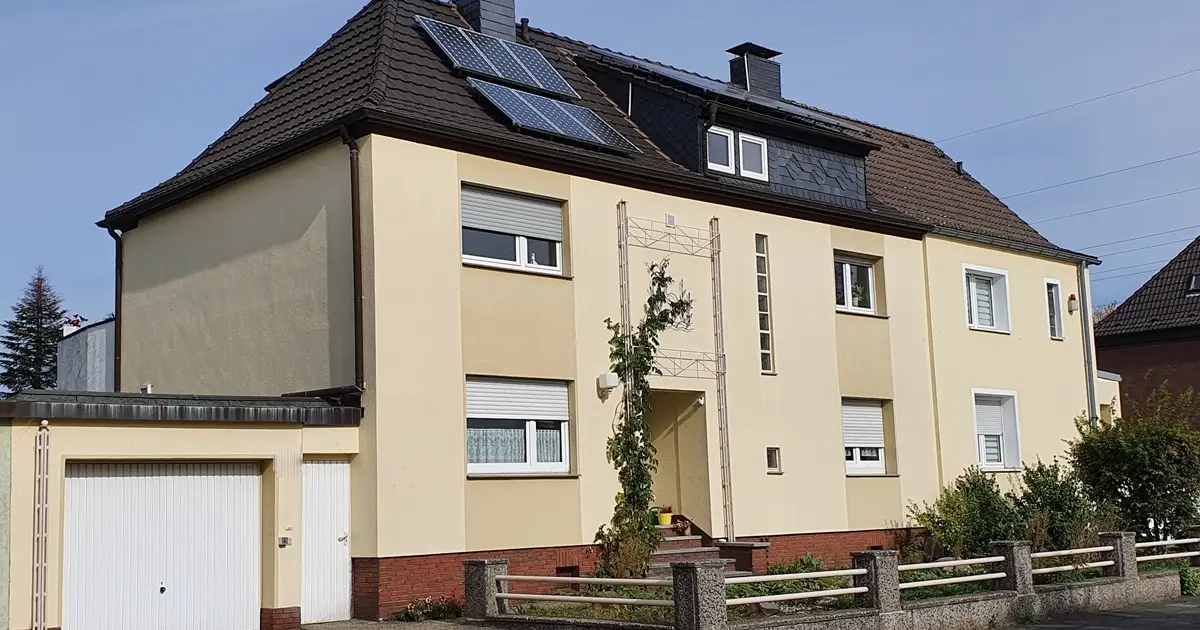 Gelbes Mehrfamilienhaus mit Solaranlage auf dem Dach