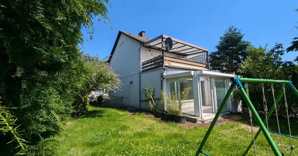 Gartenansicht mit Wintergarten und Balkon.