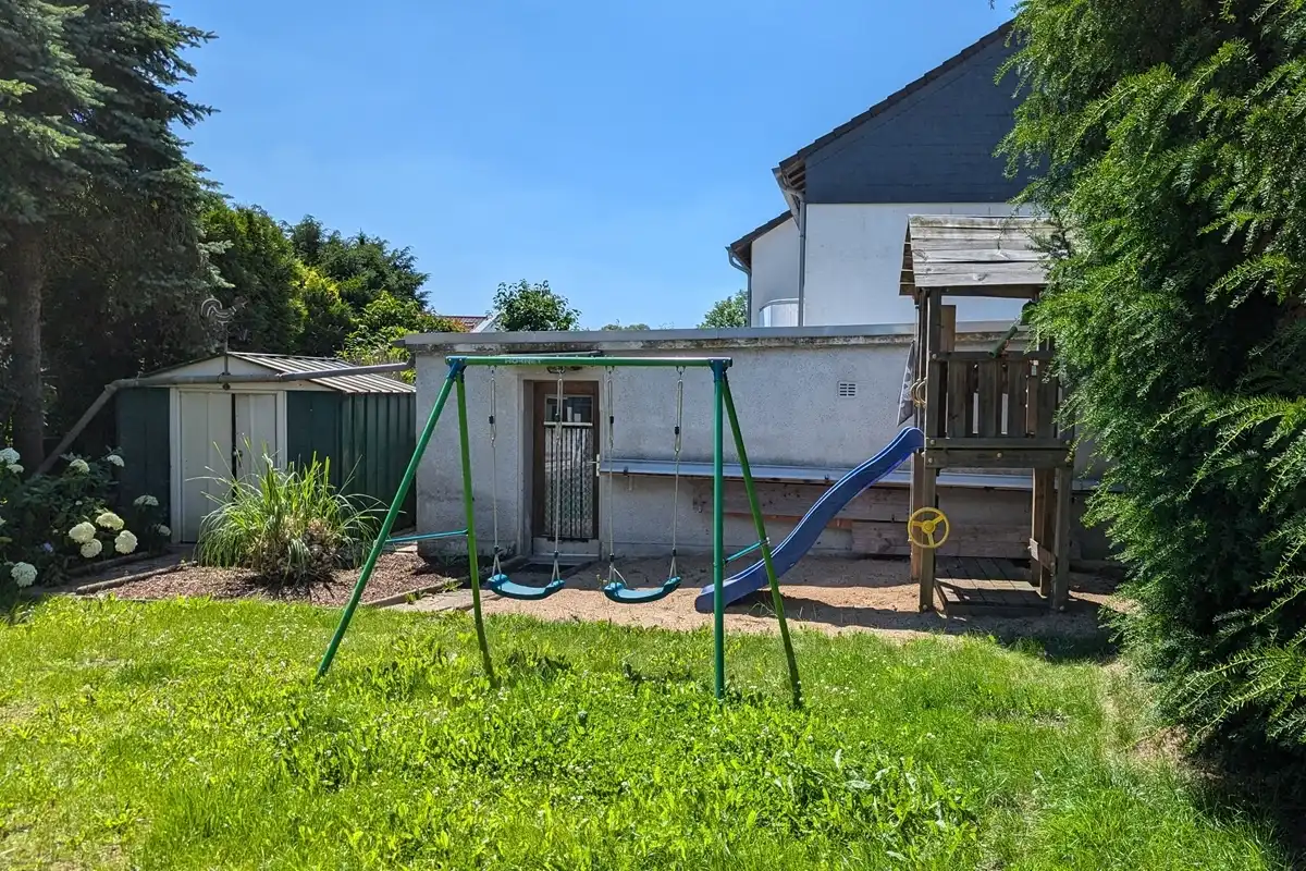 Garten mit Spielgeräten und Schuppen.