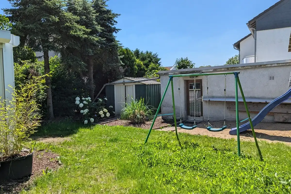 Garten mit Schaukel, Rutsche und Geräteschuppen.